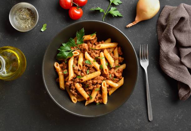 Penne pasta with minced meat, tomato sauce and greens