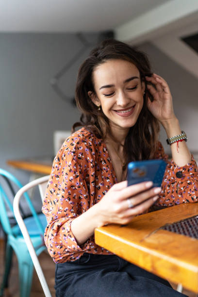 istock Beautiful young woman using mobile phone and enjoying coffee at cafe 2172430916