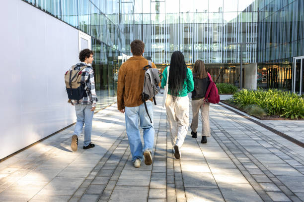 istock Back view of university students walking to class arriving at university building. Group of people in college campus. 2172433116