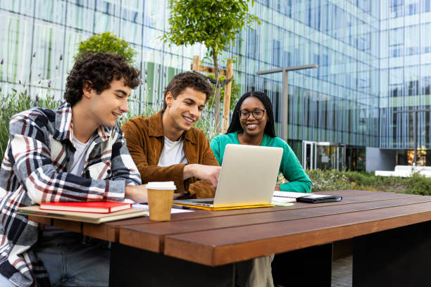 istock Happy multiracial university students studying and doing homework together outdoor in campus using laptop. Copy space 2172434754