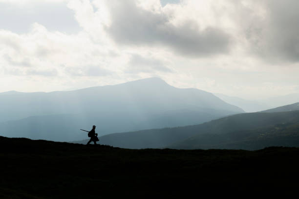 A silhouette of a photographer with a tripod against the backdrop of the majestic mountains. Landscape photography