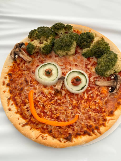 Image of creative halloween pizza faces/decorating italian pizzas with funny expressions using toppings like olives and peppers