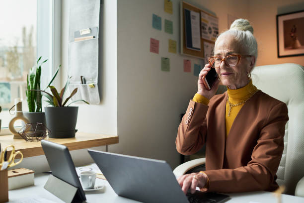 istock Elderly Woman Using Laptop and Talking on Phone 2172448419