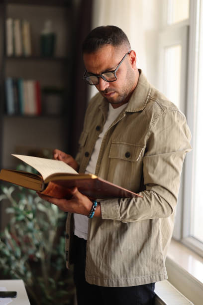 istock Mid adult man reading book in the library 2172452627