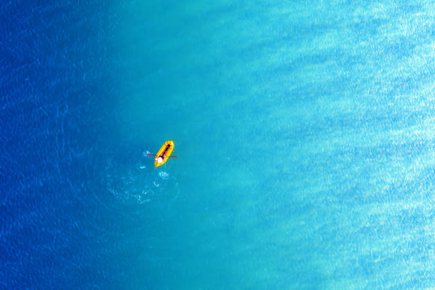 Yellow packraft rubber boat and turquoise water waves from top view. Active travel summer vacations seascape background from drone