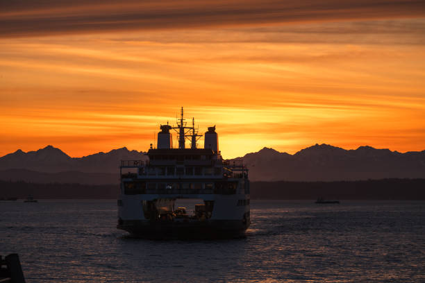 Seattle, USA – Mar 14, 2024: Golden hues illuminate elliott bay as a Ferry arrives at the brand-new Colman Ferry terminal on the waterfront in downtown.