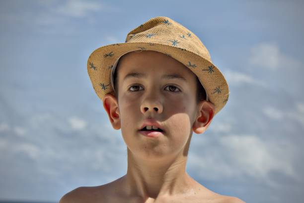 Young boy on a beach, face close up, wearing hat, Maldives