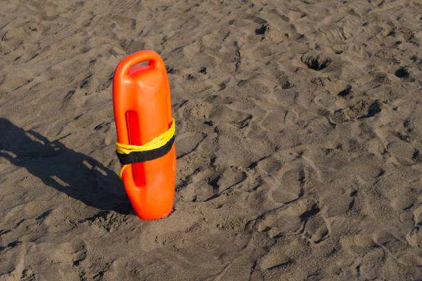 An orange lifeguard buoy is firmly planted in the sandy beach, indicating safety measures in place for swimmers. The bright color stands out against the tan sand.