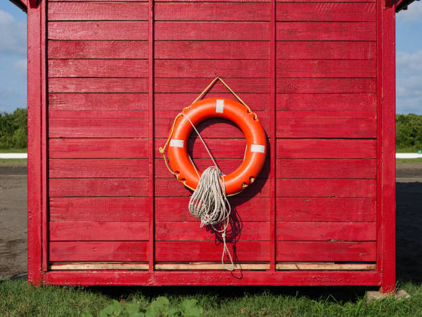 istock Bright orange lifebuoy hangs on a rustic red cabin by the shoreline 2172483025
