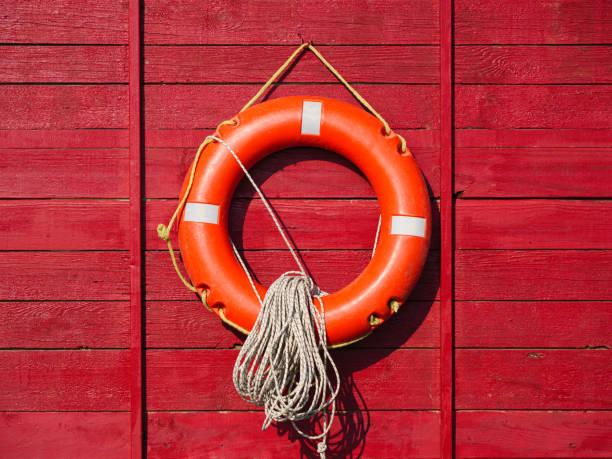 istock Bright orange life ring mounted on a red wooden wall with rope 2172483090