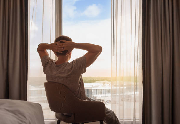 istock Happy young man relaxing looking out his apartment window. 2172484493
