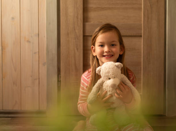 Little smiling girl holding her teddy bear.