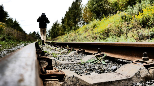 Old rusty railway rails and a traveler walking forward along them