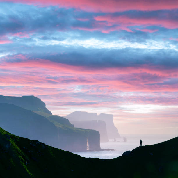Man silhouette on background of famous Risin og Kellingin rocks