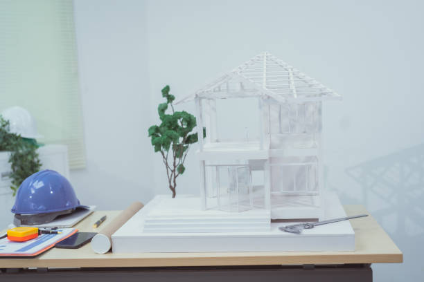 istock A home design company's office with a house sample placed on a desk, showcasing house structure design and drafting plans. The scene focuses on architecture, with no people present. 2172498373