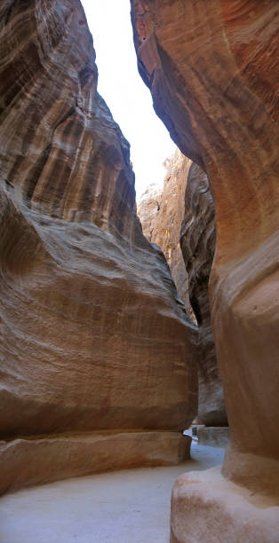 Walking in famous Petra Siq Canyon with tall stone walls and aqueduct