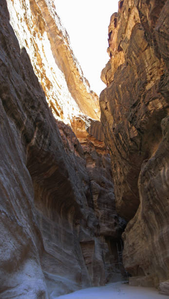 Walking in famous Petra Siq Canyon with tall stone walls and aqueduct