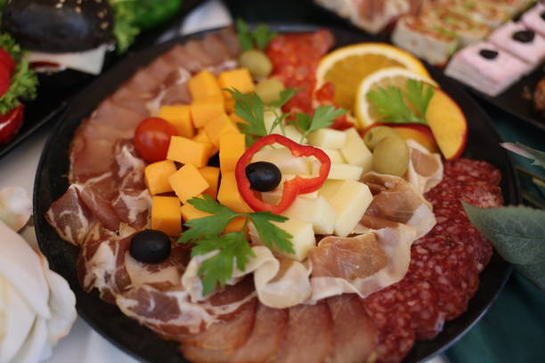 High angle shot of plate with meat and cheese on buffet table at gala event without people