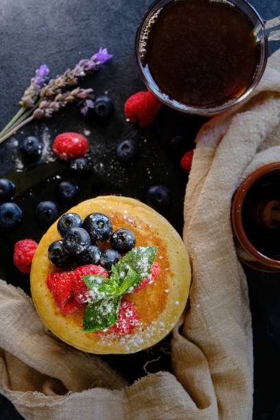 pancakes with berries and honey on dark background top view