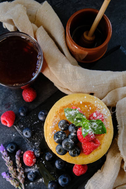 pancakes with berries and honey on dark background top view