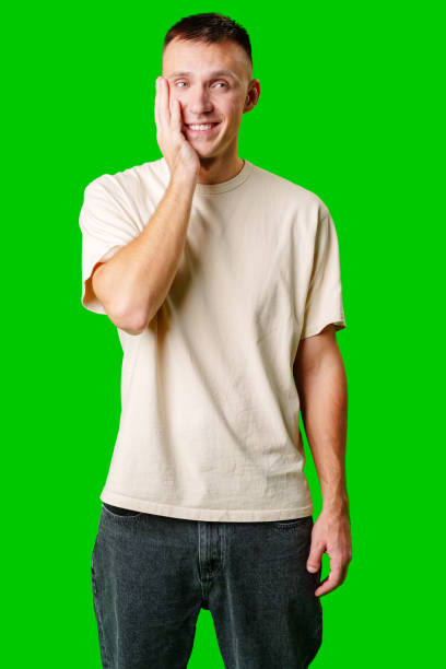 istock Young Man Smiling and Touching His Face Against a Bright Green Background 2172523882