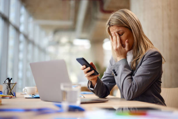istock Exhausted businesswoman having a headache while using mobile phone in the office. 2172525601