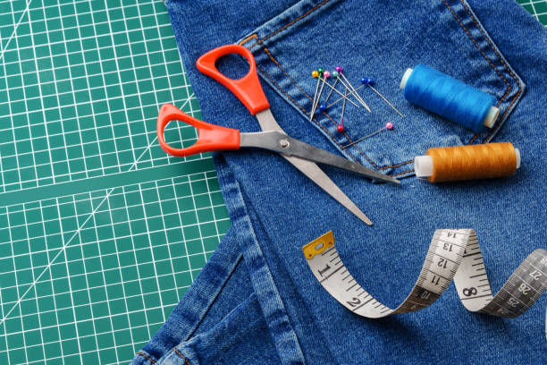 istock Sewing tools on a cutting mat with denim and thread spools in a craft workspace 2172527487
