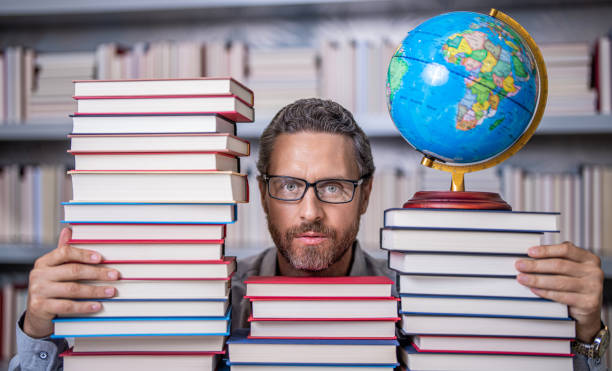 istock Knowledge and education concept. school teacher with book in classroom. teacher in classroom. Teachers Day. Tutor at classroom. Man geographer with books in classroom. love for learning 2172534478