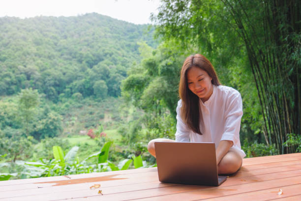 istock Portrait image of a woman using and working on laptop computer while sitting on balcony with a beautiful nature view 2172535231