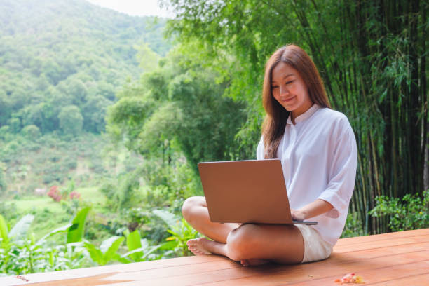 istock Portrait image of a woman using and working on laptop computer while sitting on balcony with a beautiful nature view 2172535236