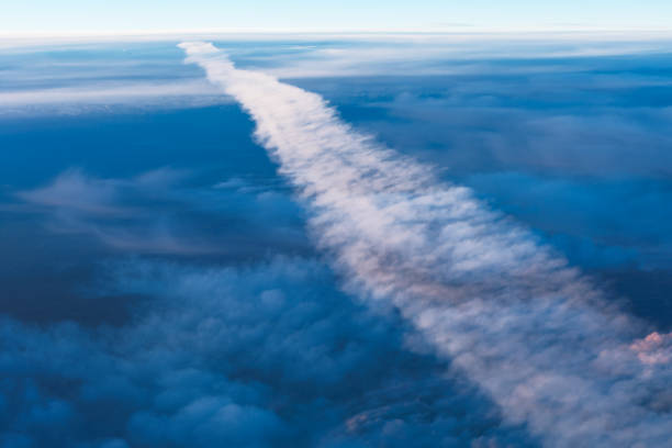 Jet trail stretches across a clear blue sky. Plane vapor trail through the clouds