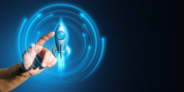 istock Hand pointing at a glowing rocket symbol on a digital blue neon background. 2172538633