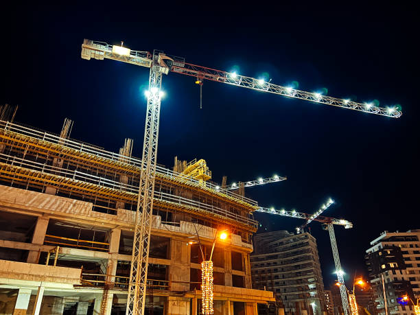 istock Construction cranes with illumination over multi-storey buildings under construction 2172539403