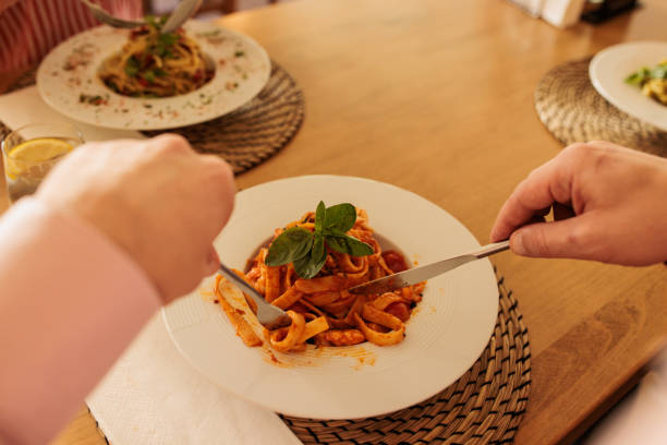 A mid adult Caucasian man eating pasta in a restaurant