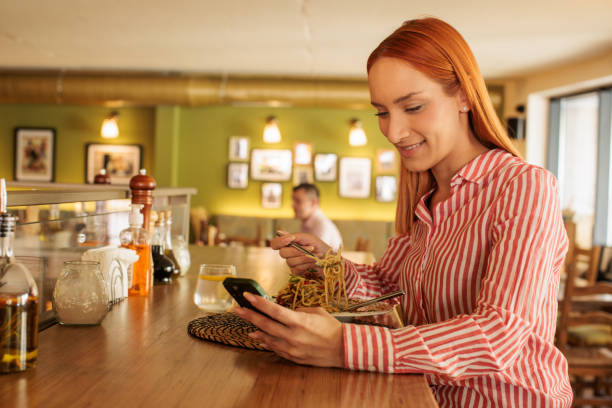istock Woman using her phone while eating in a restaurant 2172541873