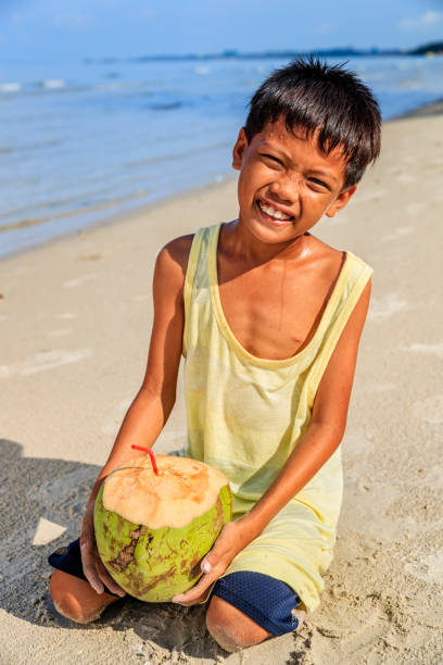 istock Cambodian young boy holding coconut on the beach, Cambodia 2172542219