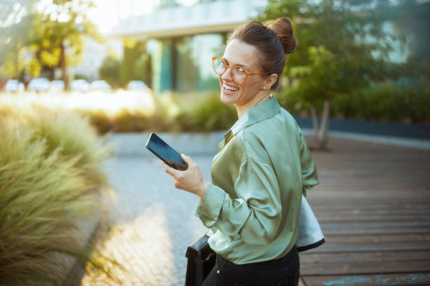 istock woman employee in green blouse using phone and walking 2172544471