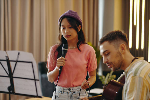 istock Singing Woman Holding Microphone with Acoustic Guitarist 2172548848