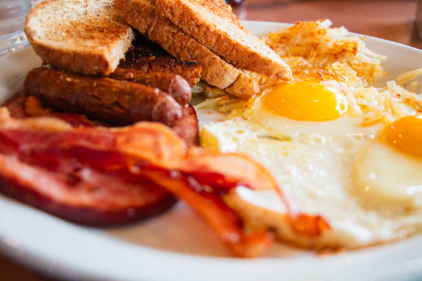 Breakfast Meal Plate With Fried Eggs, Bacon, Toast and Sausages Viewed Close-up