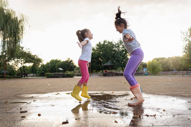 Teenage girl jumping in the rain with arms outstretched. The girl is enjoying the spring rain.\nShot with Canon R5