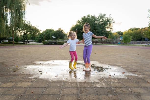 istock Two sisters having fun after rain in public park 2172550969