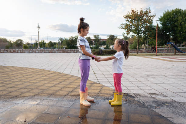 Two sisters holding hands in park and look at each other