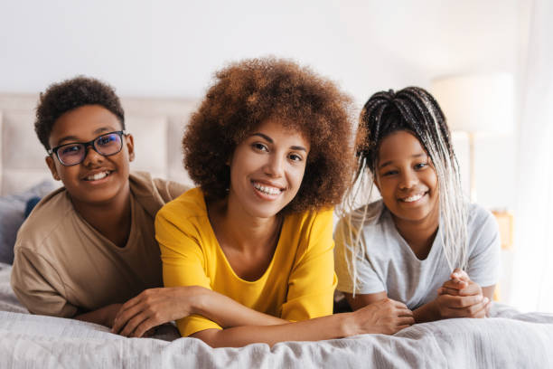 istock Young woman with two children lying on bed at home while smiling 2172551341
