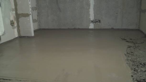 istock Leveling the floor with a spatula. Builder smoothing wet mortar on the floor. Pouring concrete. Worker uses spatula to level wet concrete on floor. 2172552441