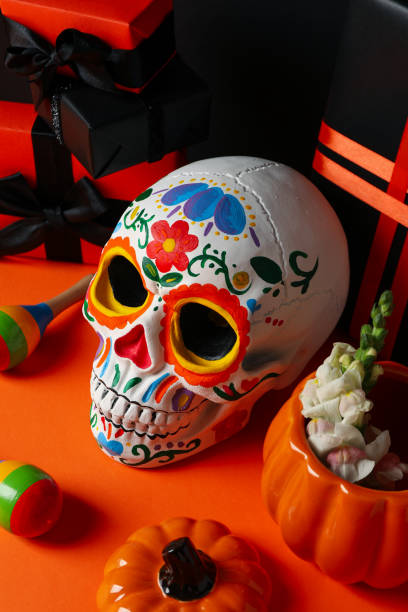 istock Mexican skull, gift boxes and pumpkin with flowers on orange background 2172555352