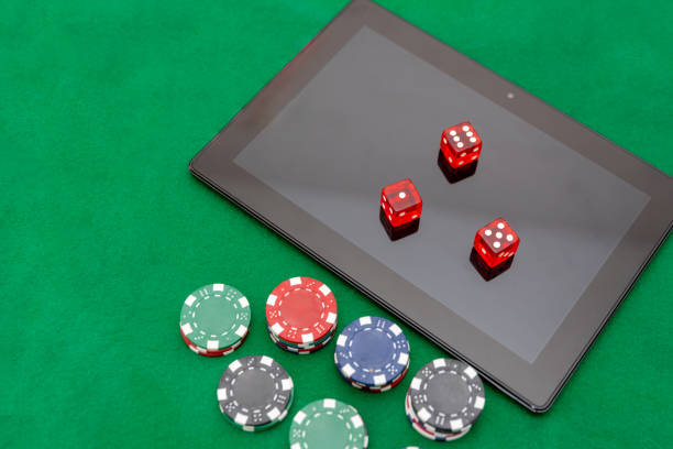 istock Digital tablet with red dice and casino chips on a green felt table, online gambling and betting 2172555767