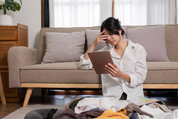 istock Young Woman Feeling Stressed While Preparing Her Suitcase for a Trip, Sitting on the Floor with Clothes and Tablet 2172558787