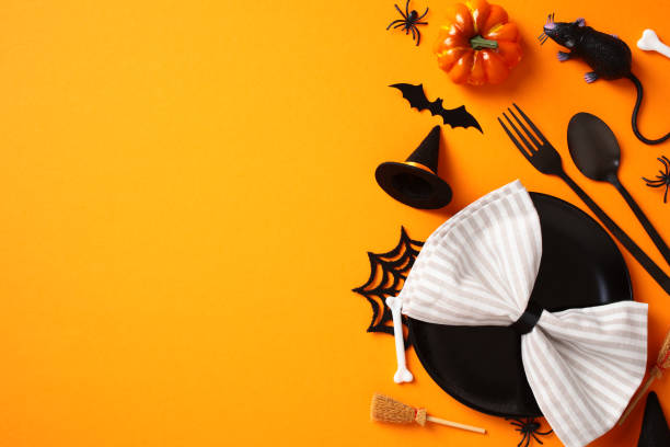 istock Halloween table setting with napkin on black plate, cutlery, pumpkins, festive decorations on orange background. 2172559796