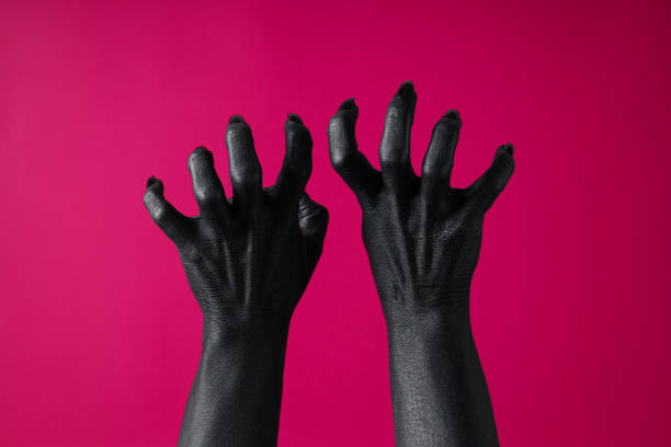istock Black female hands with black nails on pink background 2172559924