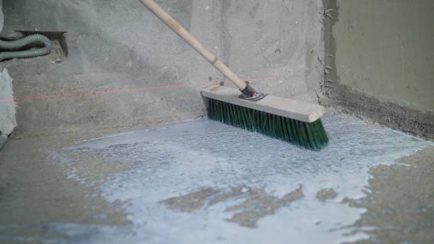 istock Primer for concrete floor. The master lays liquid soil on a concrete floor. Primer worker on concrete floor. Primer floor protection in a new room 2172563886